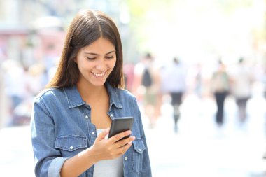 Mutlu kız büyük bir şehir sokakta yürürken bir akıllı telefon kullanır
