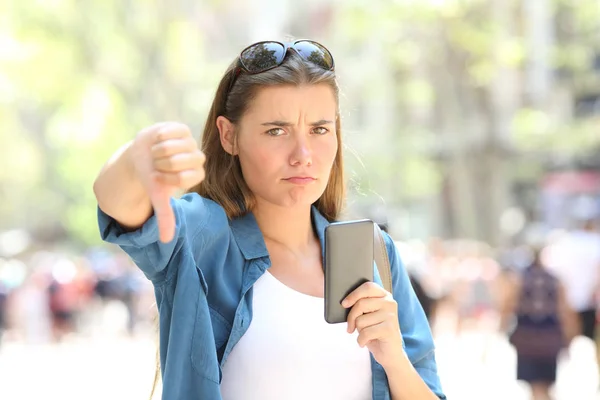 Mulher Irritada Segurando Telefone Inteligente Olhando Para Câmera Com Polegares — Fotografia de Stock
