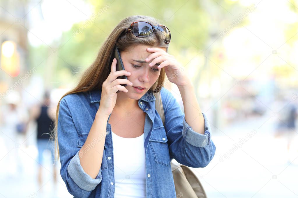 Worried woman having a mobile phone conversation walking in the street