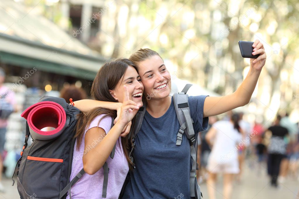 Backpacker friends taking selfie with a smart phone in the street