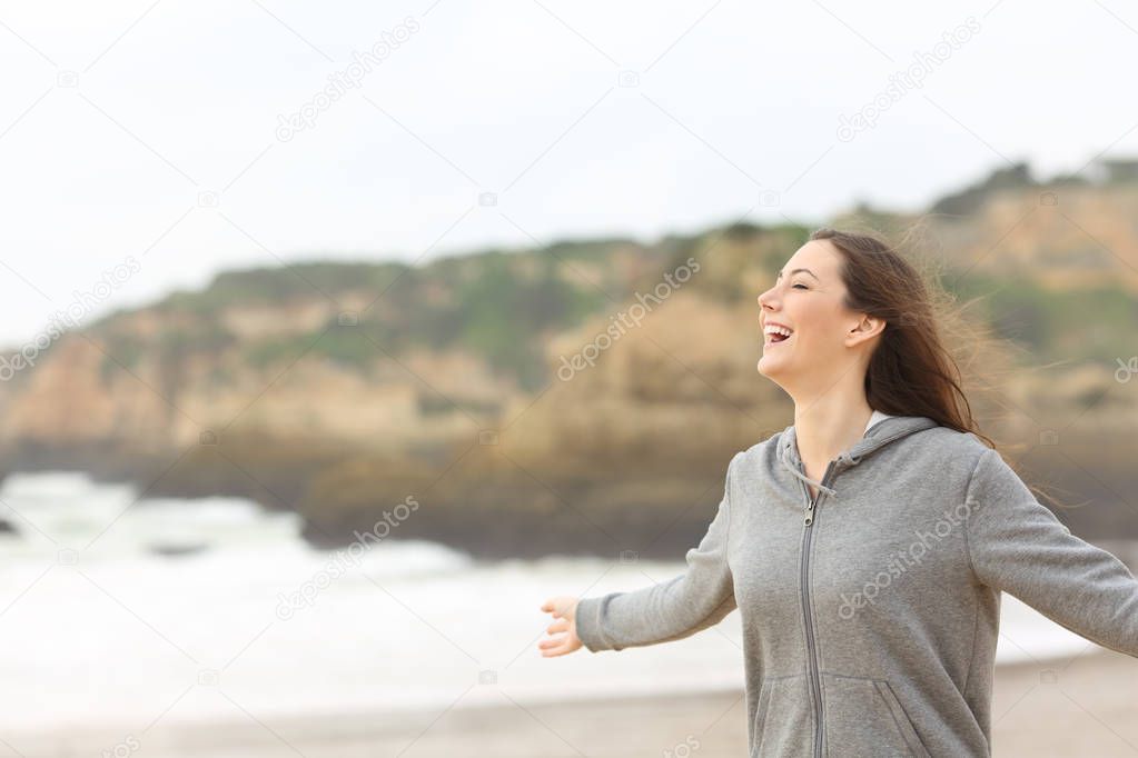 Cheerful teenage girl stretching arms laughing on the beach