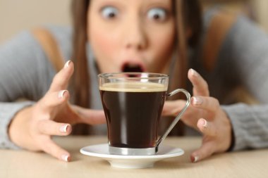 Front view portrait of an amazed woman looking at coffee cup clipart