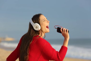 Şarkı ve sahilde akıllı telefon ve kulaklık ile müzik dinlemek kırmızı komik teen