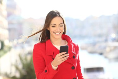Bayan kırmızı kış bir sahil kasabası sokakta yürürken bir akıllı telefon kullanır