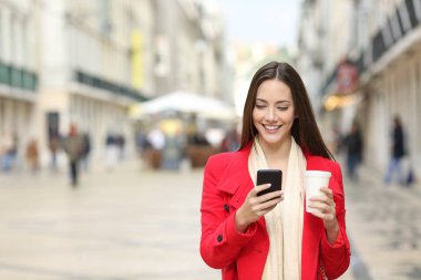 Yanında kopya alanı ile kışın bir akıllı telefon kullanarak sokakta yürüyen mutlu bir kadın portresi önden görünüm