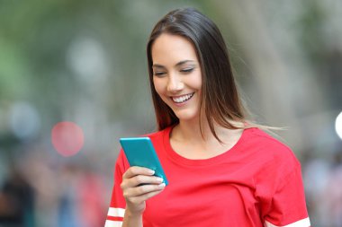 Sokakta yürürken mavi bir akıllı telefon kullanarak kırmızı mutlu teen