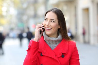 Sokakta kışın kırmızı telefonla konuşmaktan mutlu kadın