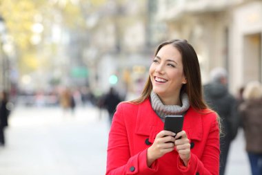 Mutlu kadın kopya boşluk sokakta kışın bir telefon tutarak yan bakarak