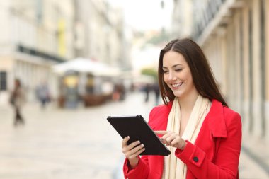 Mutlu kadın bir tablet eski bir şehir sokakta kışın kullanır