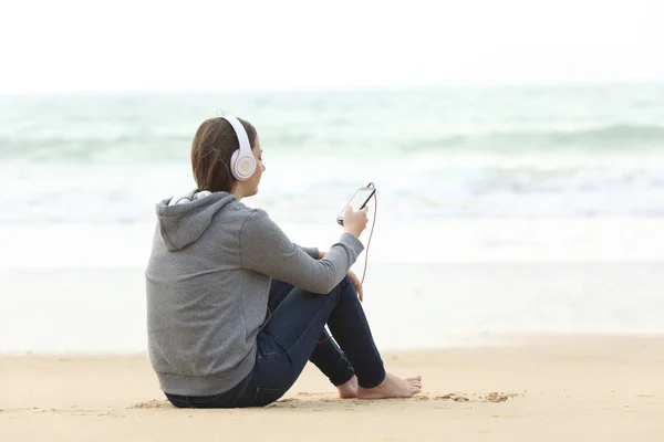 渴望的青少年独自听音乐坐在沙滩上的沙滩上 — 图库照片