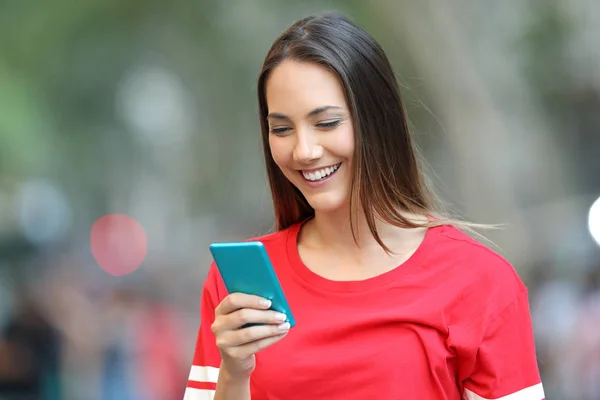快乐的青少年在红色使用蓝色智能手机走在街上 — 图库照片