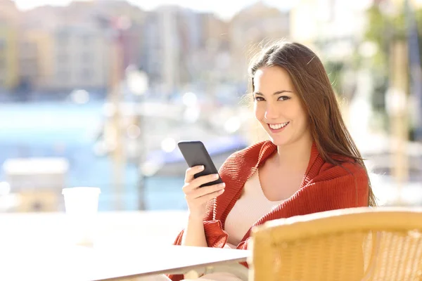 Mujer Feliz Sosteniendo Teléfono Inteligente Una Cafetería Mirándote Una Calle — Foto de Stock