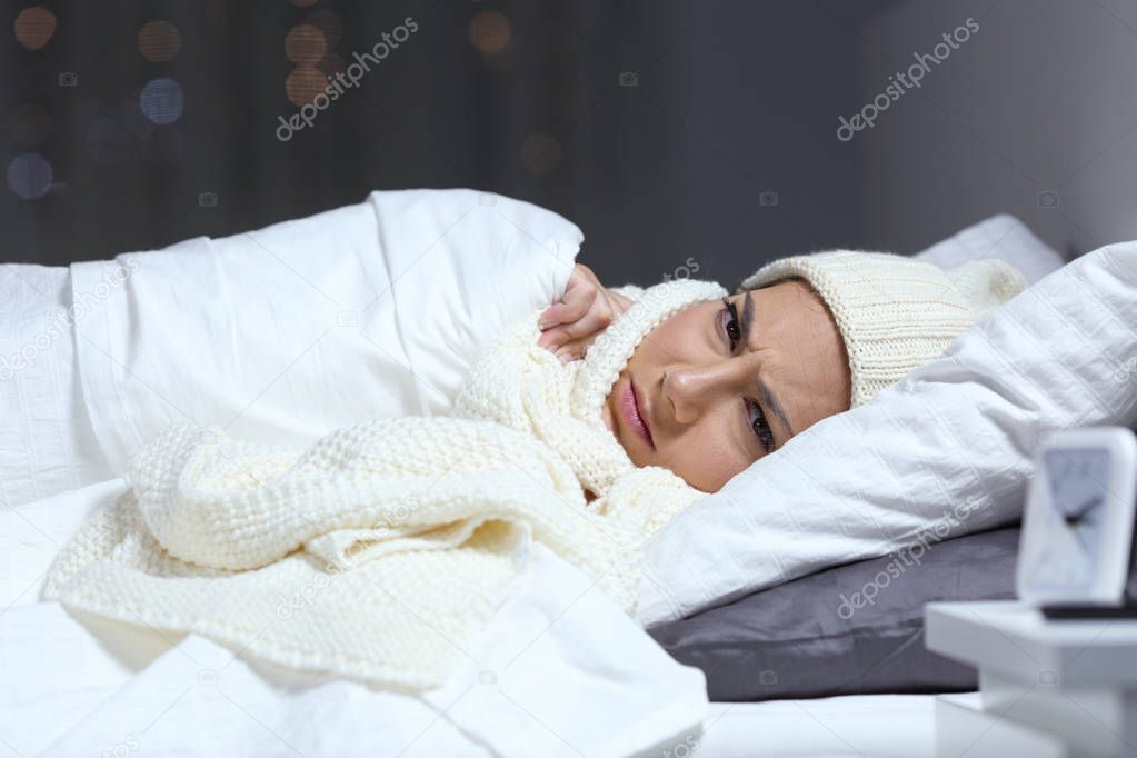 Angry woman keeping warm in the bed in a cold winter night at home