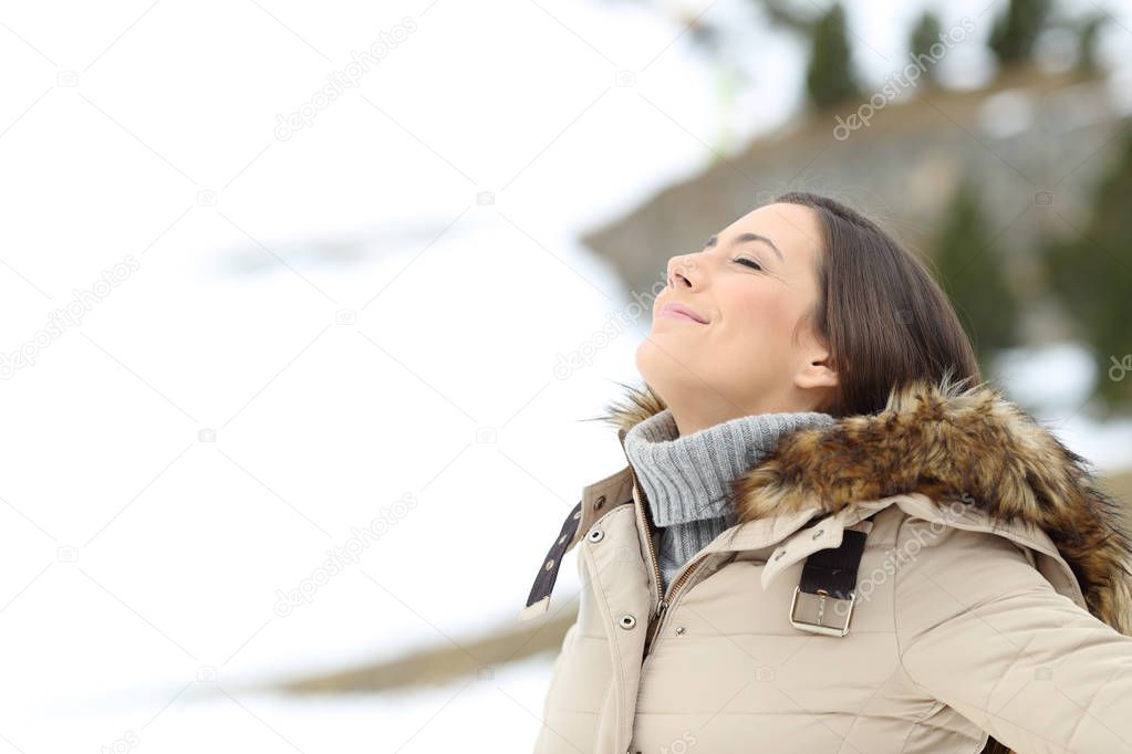 Happy lady breathing fresh air on winter holiday in a cold snowy mountain
