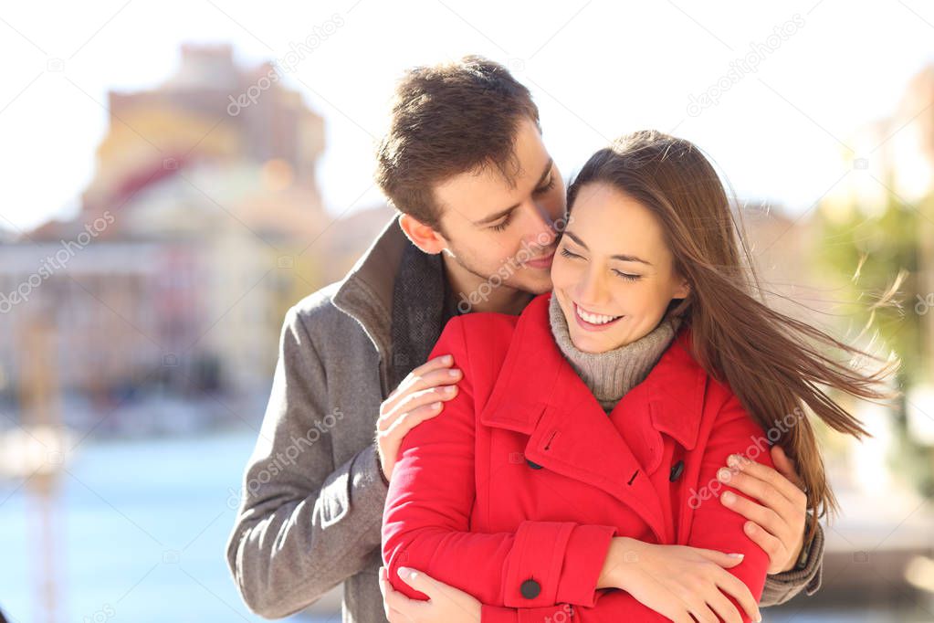 Man seducing a woman whispering on ear in a town street in winter holiday