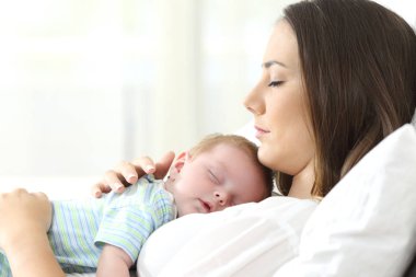 Profil ciddi bir annenin bebeği ile bir yatakta uyumak