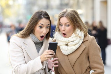 Sokakta kışın telefon içeriğini okumaya iki sürpriz kadın portresi önden görünüm