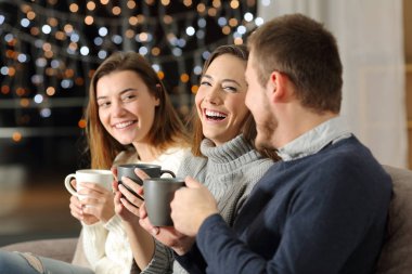 Söz ve oturma odasında evde bir kanepede oturan gece gülüyor üç arkadaş