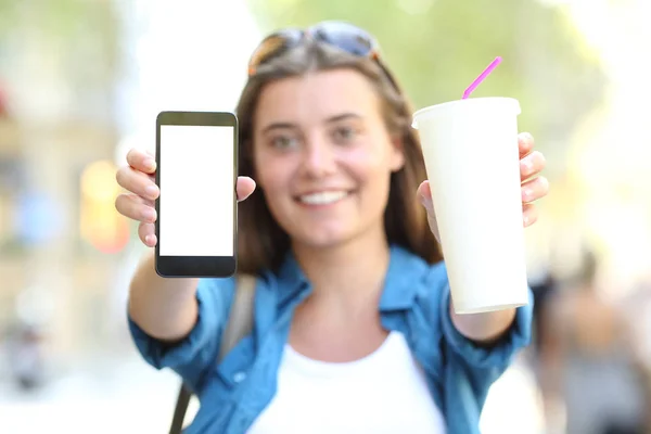 通りでテイクアウトのガラスと携帯電話の画面を示す幸せな女の子の正面肖像画 — ストック写真