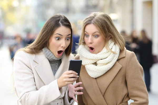 Retrato Vista Frontal Dos Mujeres Sorprendidas Leyendo Contenido Del Teléfono —  Fotos de Stock