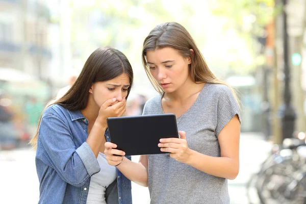 两个担心的朋友在街上的平板电脑上阅读在线新闻 — 图库照片