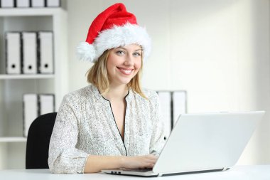 İşyeri kameraya bakarak Noel Baba şapkası giyen poz ofis çalışanı