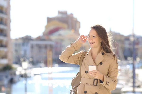 Mujer Feliz Sosteniendo Teléfono Inteligente Tocando Cabello Caminando Calle Otoño —  Fotos de Stock