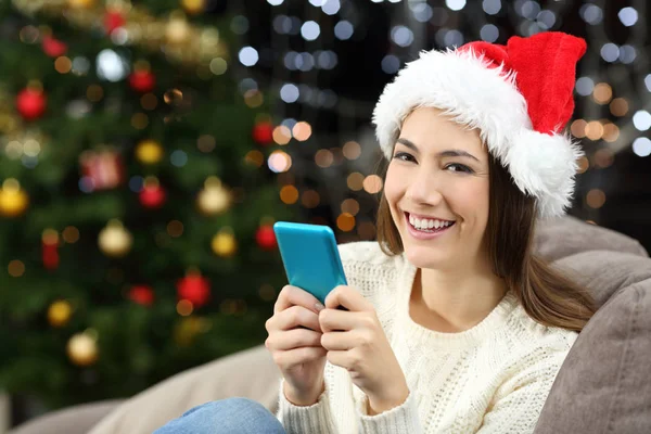 Mulher Segurando Telefone Inteligente Olhando Para Câmera Natal Sentado Sofá — Fotografia de Stock