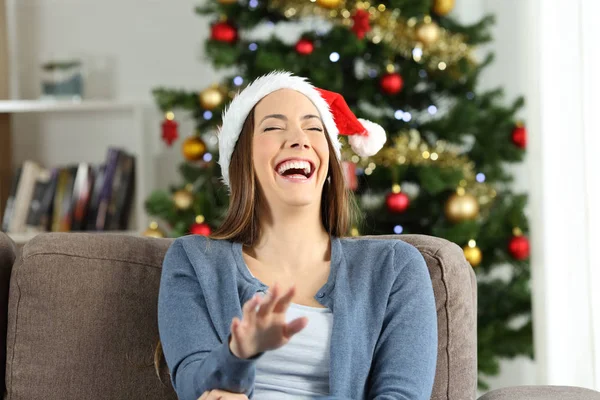 Woman laughing loud on christmas sitting on a couch in the living room at home