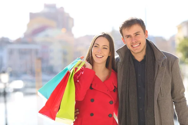 前视图肖像的一对快乐的情侣在冬季散步举行购物袋 — 图库照片