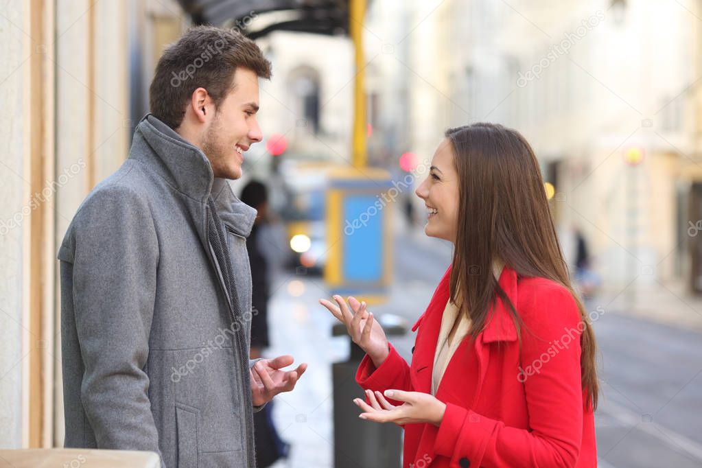 Profile of a happy couple talking in winter in the street of an old town