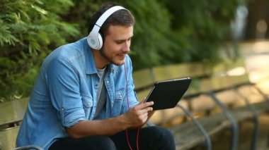 Hatta bir parkta bir bankta oturmuş bir Tablet video izlemek rahatlatıcı mutlu bir erkek portresi