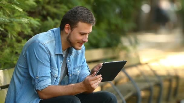 Hombre Feliz Navegando Contenido Línea Una Tableta Sentada Banco Parque — Vídeo de stock