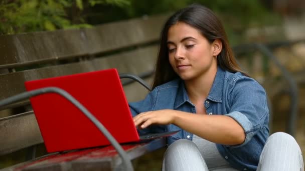 集中的妇女打字在笔记本电脑上的长凳上公园 — 图库视频影像