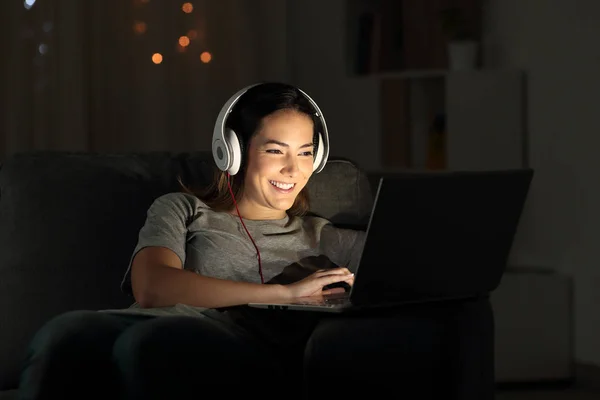 快乐的女孩在线教学与笔记本电脑在晚上坐在沙发上的客厅在家里 — 图库照片