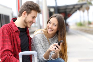 Mutlu çifte bir tren istasyonunda bir akıllı telefon olarak çevrimiçi içerik söz