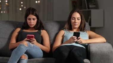 Her akıllı telefonlar oturma odasında evde bir kanepede oturan kullanarak diğer görmezden sıkılmış antisosyal arkadaşlar