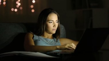 Evde bir kanepede oturan bir dizüstü bilgisayar ile gece geç saat online çalışan girişimci