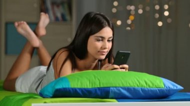 Mesaj yazarken bir akıllı telefon bir yatağa evde gece mutlu bir genç görünümünü tam vücut