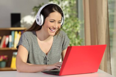 Mutlu kız e-öğrenme izlerken video tutorials ile bir laptop ve kulaklık, evde