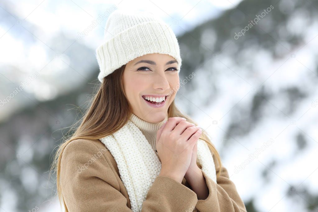 Happy woman heating hands in winter holiday in the mountain