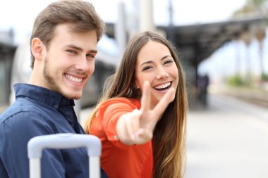 Çift kamera bir tren istasyonunda bakarak poz mutlu yolcuları
