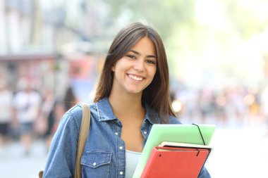 Kamera sokakta bakarak klasörler pozlar tutan mutlu öğrenci