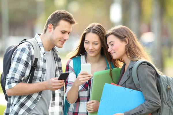 Tres Estudiantes Relajados Viendo Contenido Teléfonos Inteligentes Afuera Parque —  Fotos de Stock