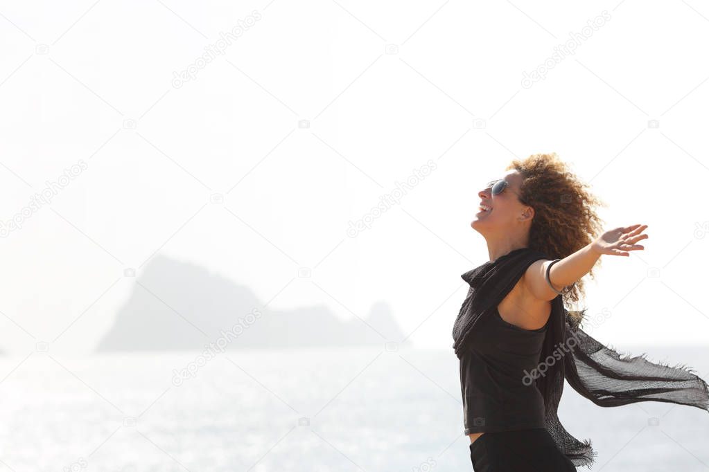 Side view portrait of a happy woman breathing on the beach with an island in the background