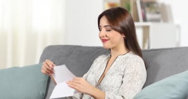 Mutlu kadın evde bir kanepede oturan bir mektup okuma