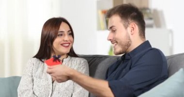 Mutlu bir adam verir bir hediye kartı bir kanepede oturan kız evde Anasayfa
