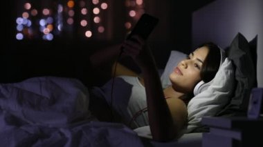 Heyecanlı genç gece evde bir telefondaki yatakta iyi haber okuma
