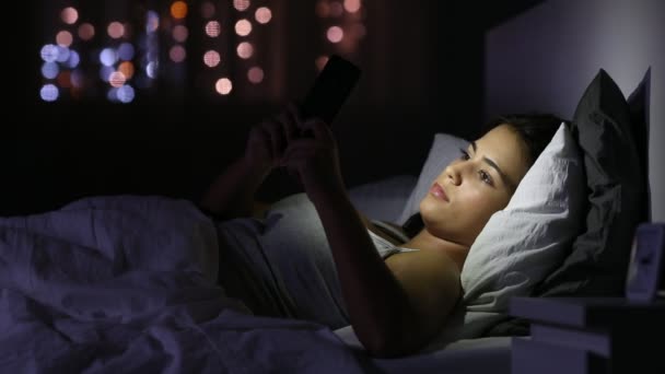 Menina Séria Conversando Com Telefone Inteligente Deitado Cama Noite Casa — Vídeo de Stock