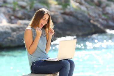 Heyecanlı kadın online teklif bir dizüstü bilgisayarda yaz tatile sahilde bulma
